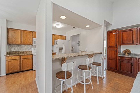A kitchen with white chairs and wooden cabinets.