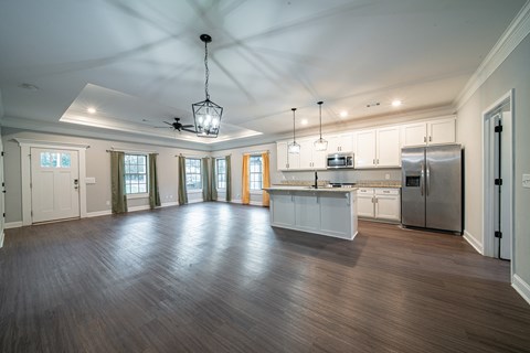 A spacious kitchen with white cabinets and a wooden floor.