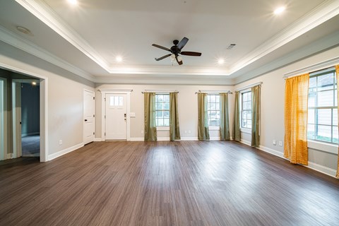 A spacious room with wooden floors and a ceiling fan.