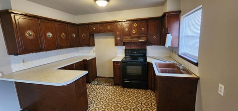 A kitchen with brown cabinets and a black stove top oven.