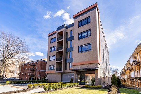 A modern apartment building with a red brick exterior and a mix of beige and blue windows.