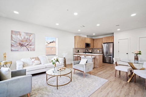 A modern living room with a grey sofa, a coffee table, and a kitchen in the background.