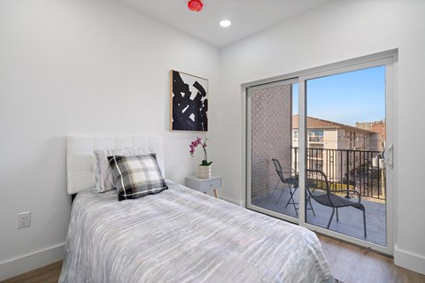 A bedroom with a bed, chair, and painting on the wall.