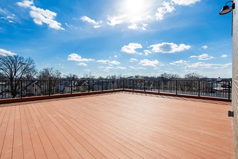 A wooden deck with a metal railing and a view of the sky.