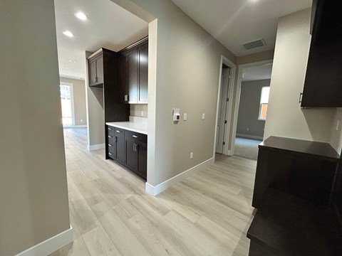 A kitchen with black cabinets and a wooden floor.