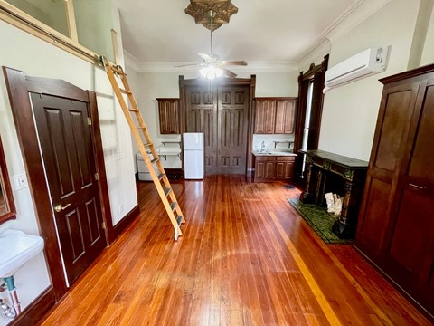 A room with wooden floors and a ladder in it.