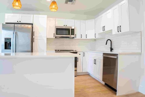 A kitchen with white cabinets and a refrigerator.