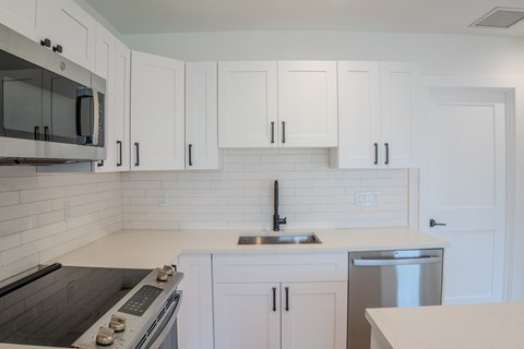 A kitchen with white cabinets and a black stove top.