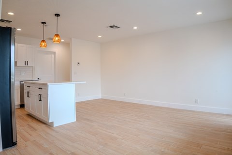 A kitchen with white cabinets and a wooden floor.