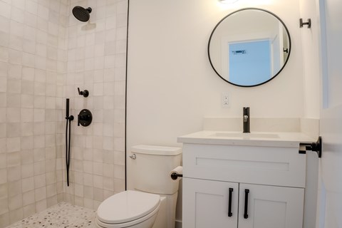 A white toilet with a black flush handle sits next to a white sink with a black faucet.