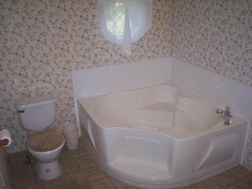 A white toilet sits next to a white bathtub in a bathroom.