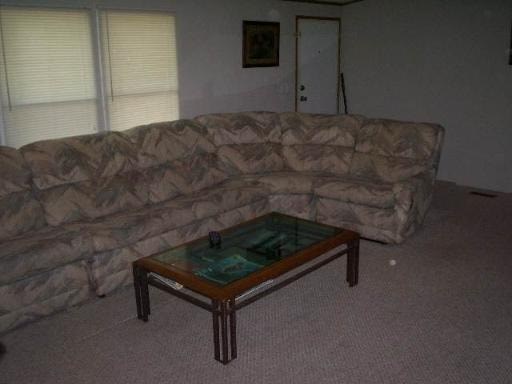 A camouflage couch sits in a living room with a coffee table in front of it.