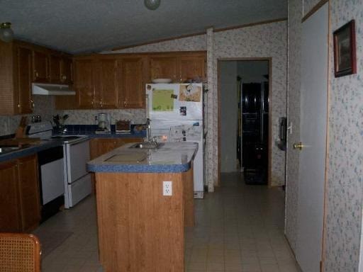 A kitchen with a refrigerator, sink, and cabinets.