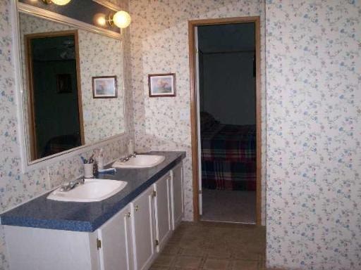 A bathroom with a mirror, sink, and two pictures on the wall.