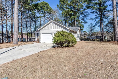 A house with a garage and a driveway surrounded by trees.