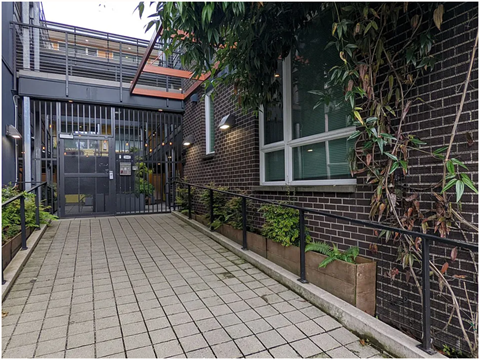 A brick building with a black gate and a tiled walkway.