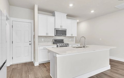 A white kitchen with a sink and a microwave.