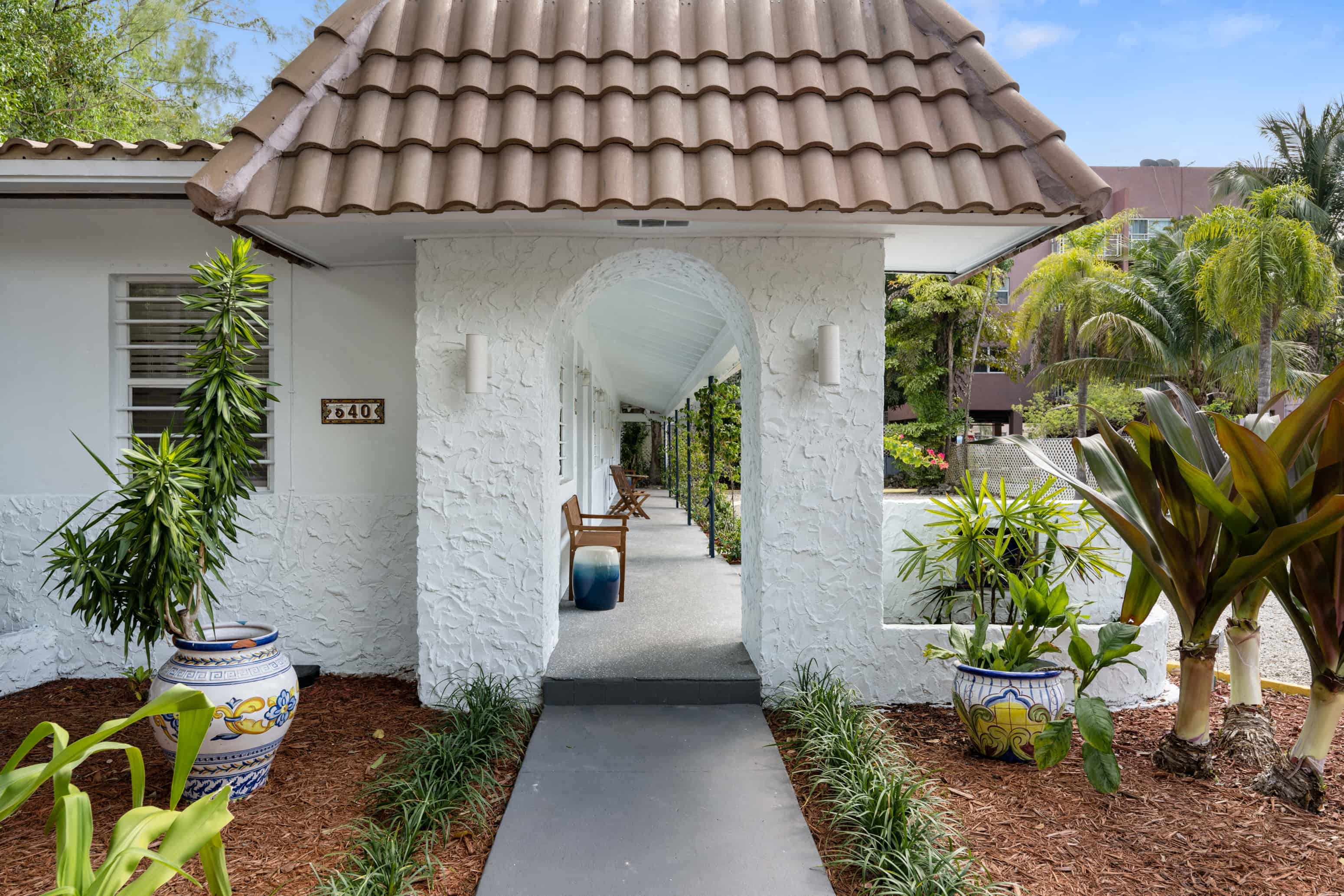 A white house with a brown roof and a white archway.