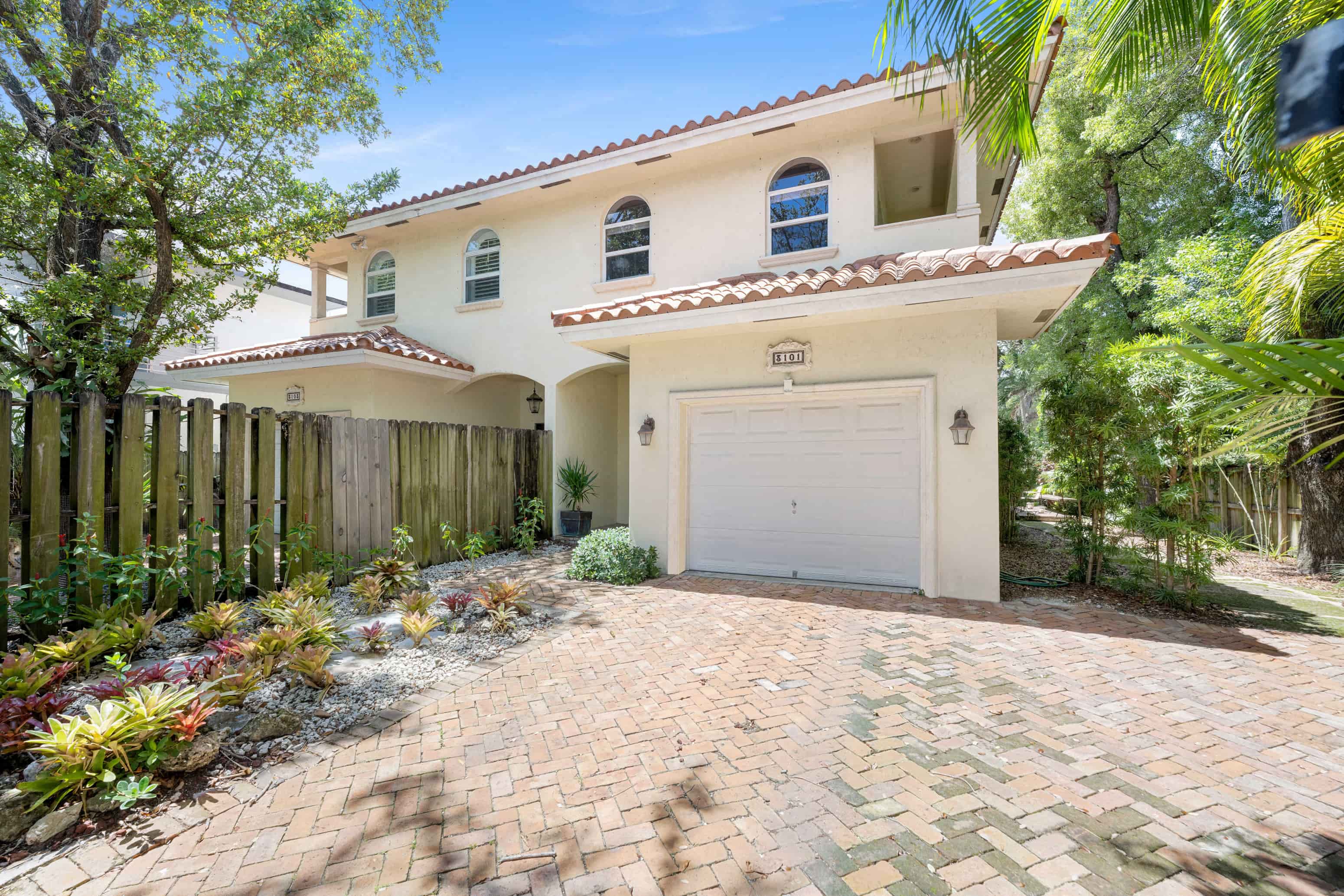 A house with a white garage door and a brick driveway.
