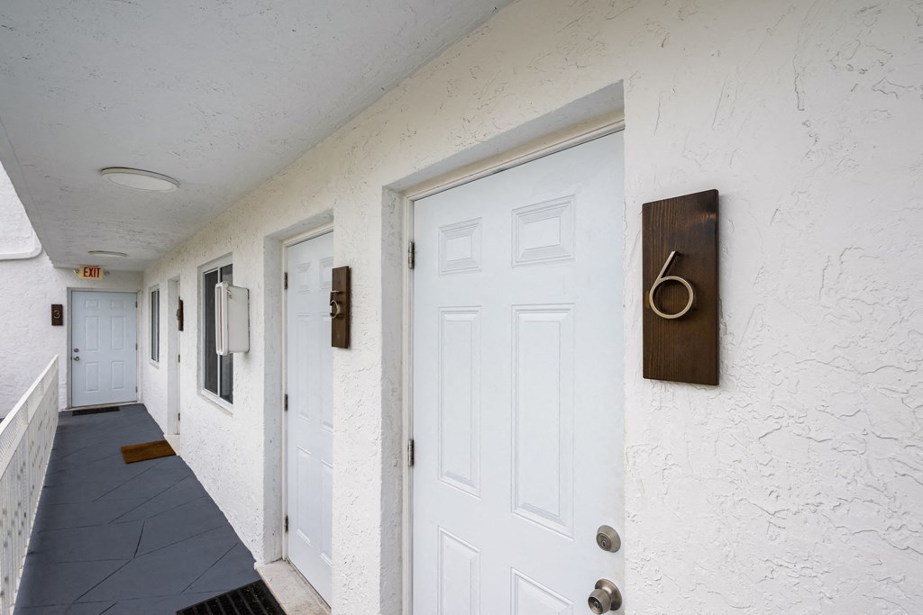 A hallway with white doors and a brown number 6 on the wall.