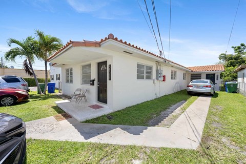 A white house with a red tile roof and a small front yard.