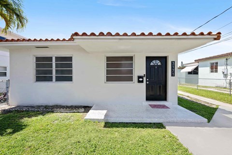 A small white house with a black door and windows.