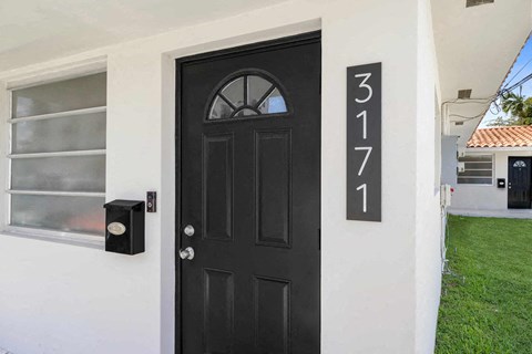A black door with the number 3171 on the wall above it.