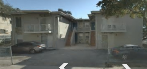 A car is parked in front of a two-story building.