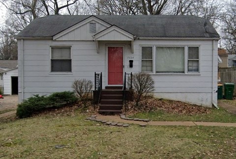 A small house with a red door and a window with white curtains.