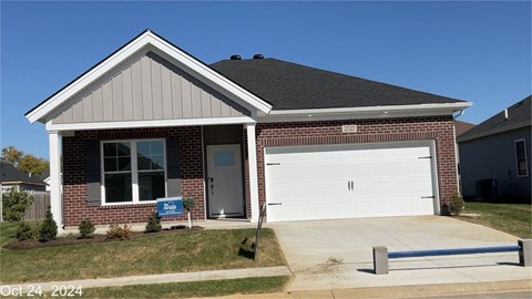A house with a garage and a blue sign in front of it.