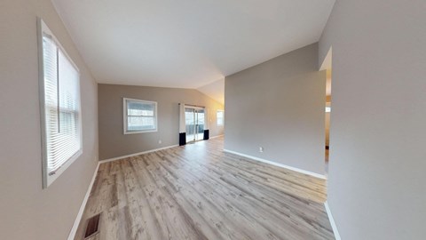 A spacious room with wooden flooring and white walls.