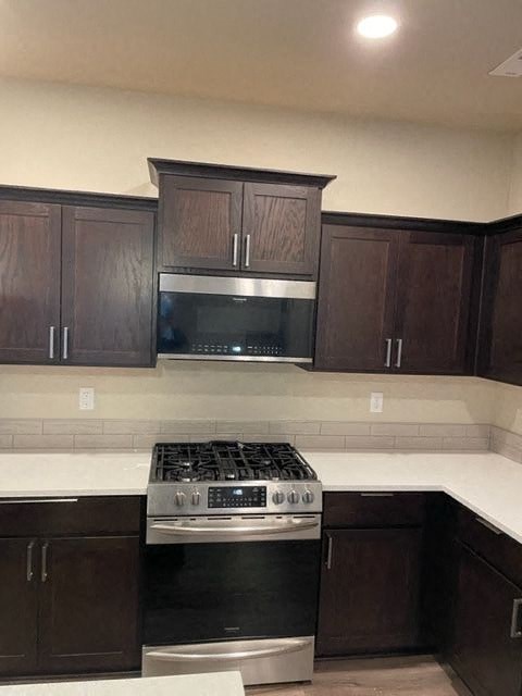 A kitchen with dark brown cabinets and a stainless steel oven.