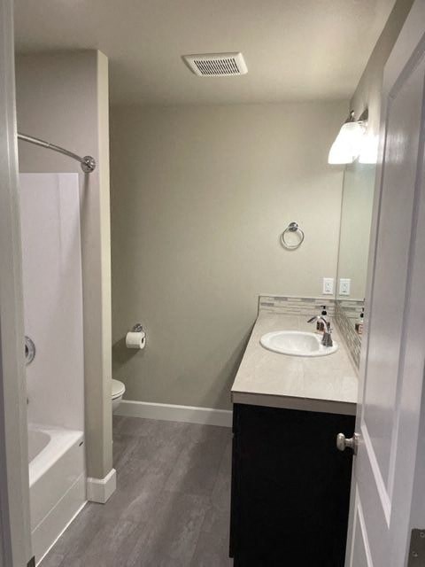 A bathroom with a sink, mirror, and toilet paper roll.