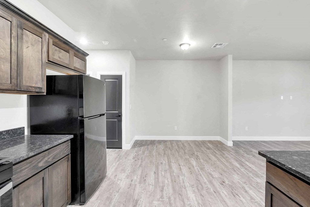 A kitchen with a black fridge and wooden cabinets.