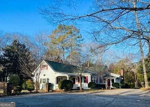 A white house with a green roof is surrounded by trees.