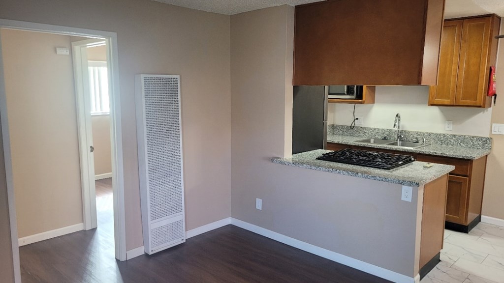 A kitchen with a granite countertop and wooden cabinets.