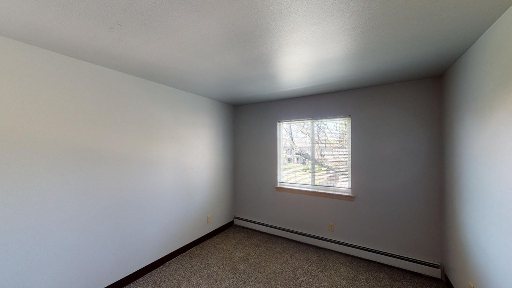 A room with a window and carpeted floor.