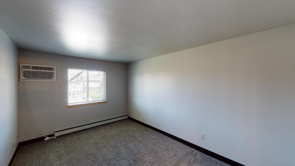 A room with a window and a carpeted floor.