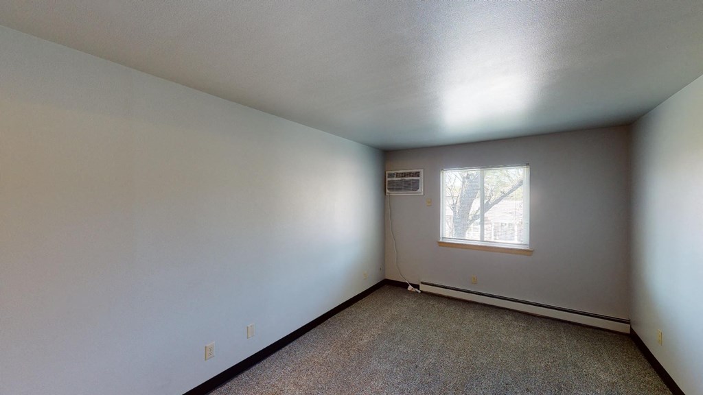 A room with a window and carpeted floor.