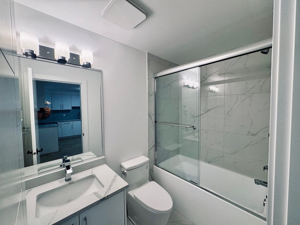 A white bathroom with a sink, toilet, and shower.