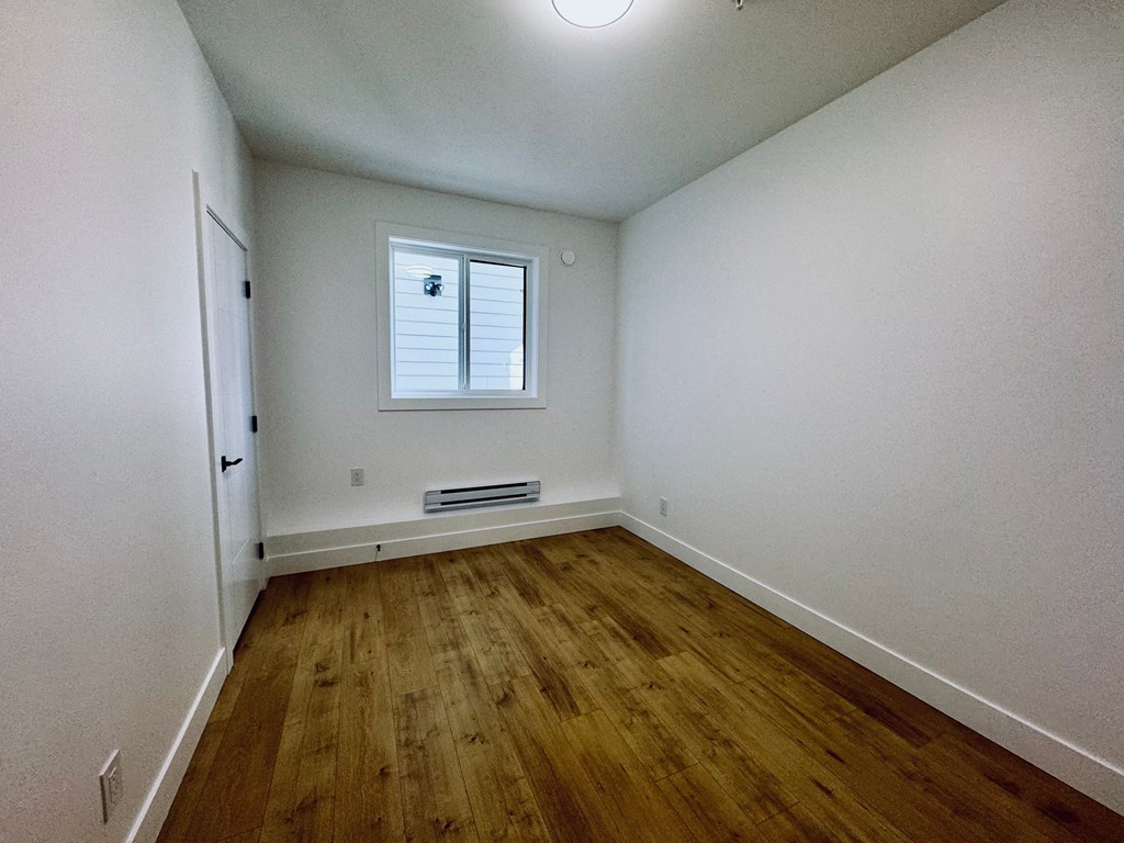 A room with wooden flooring and a window.