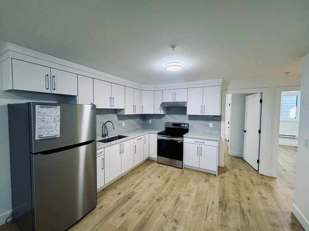 A kitchen with white cabinets and a stainless steel refrigerator.