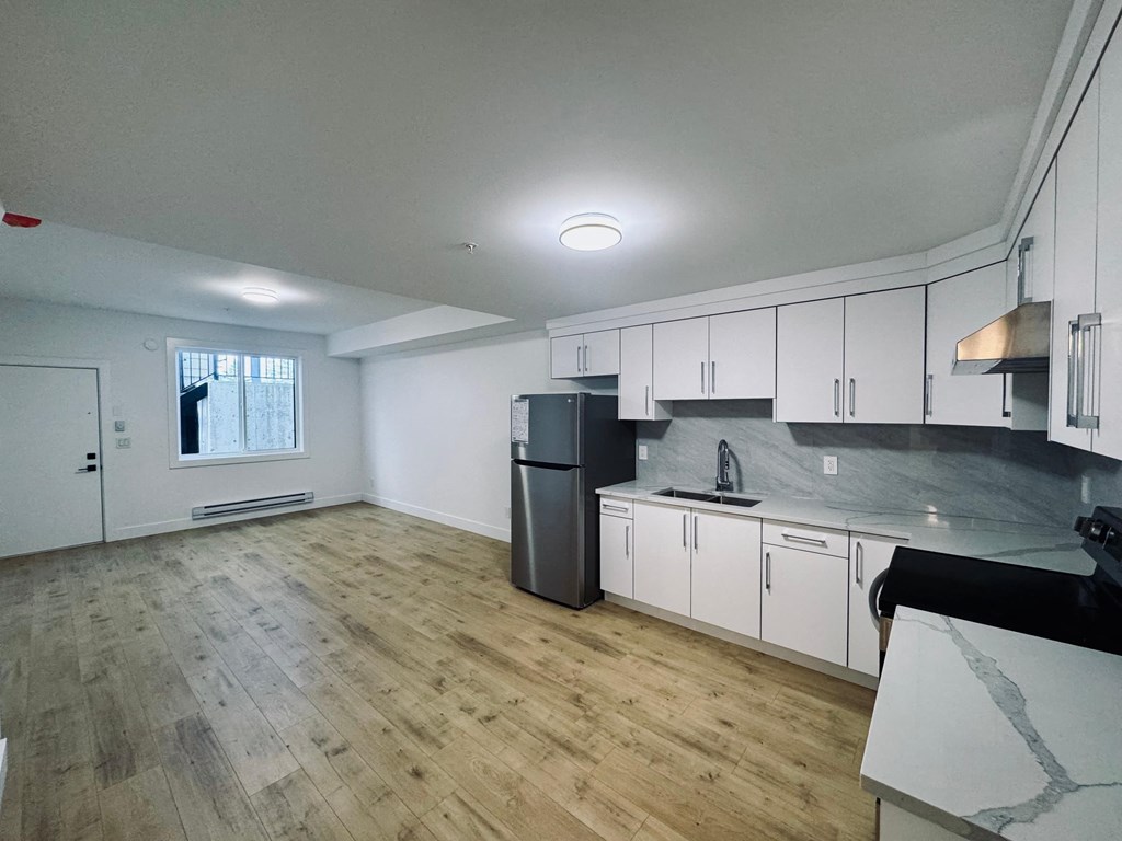 A kitchen with white cabinets and a black countertop.