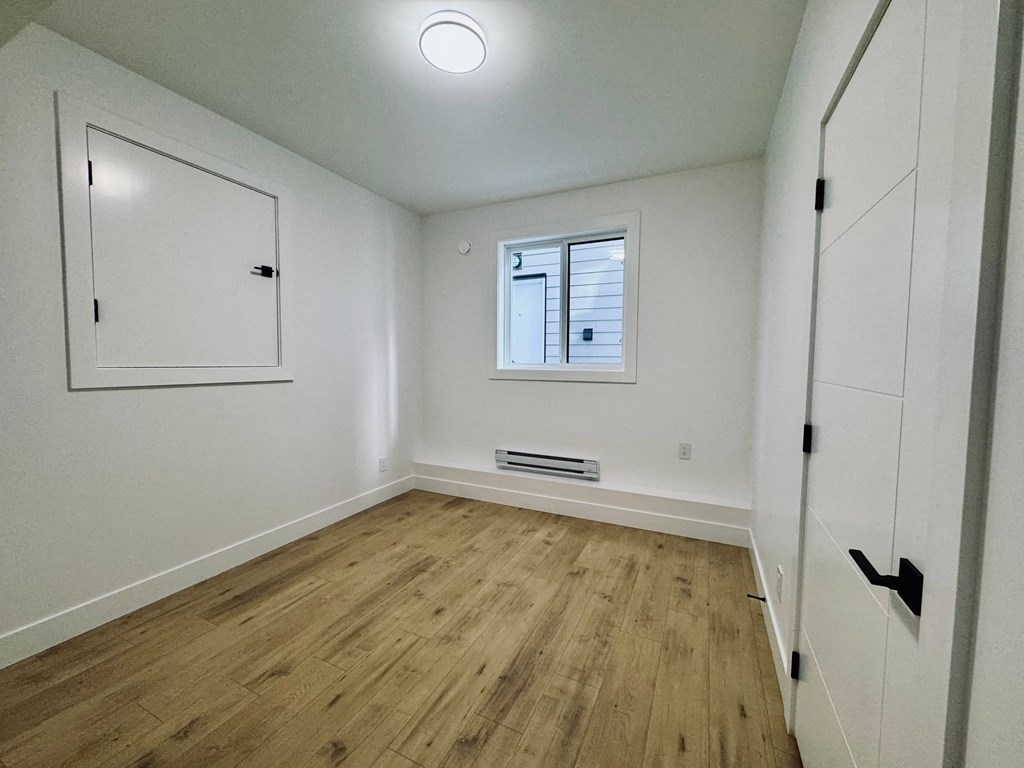 A room with wooden flooring and white walls.