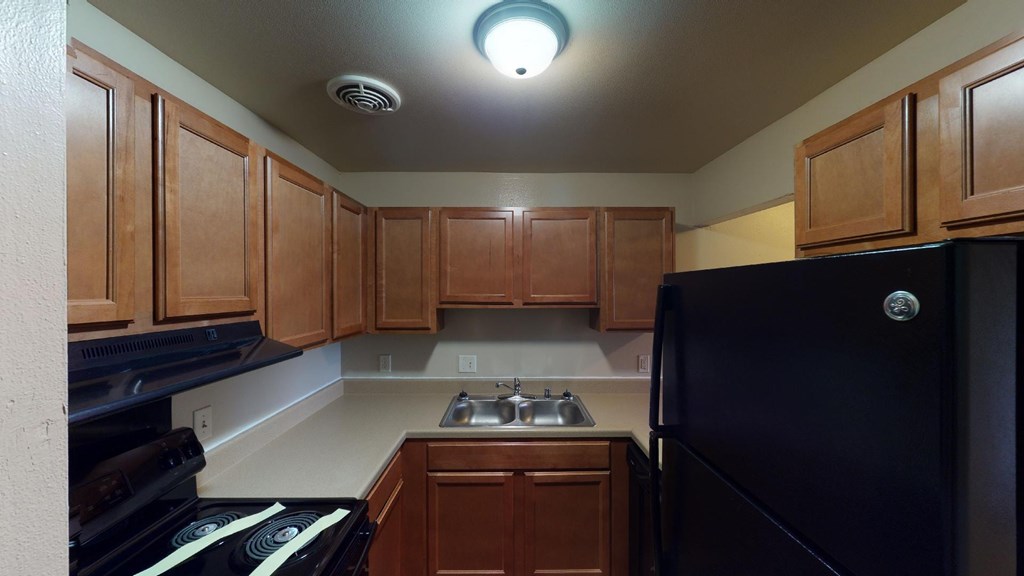 A kitchen with wooden cabinets and a black refrigerator.