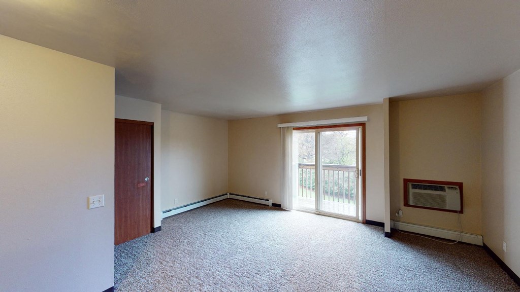 A room with a carpeted floor and a window with blinds.