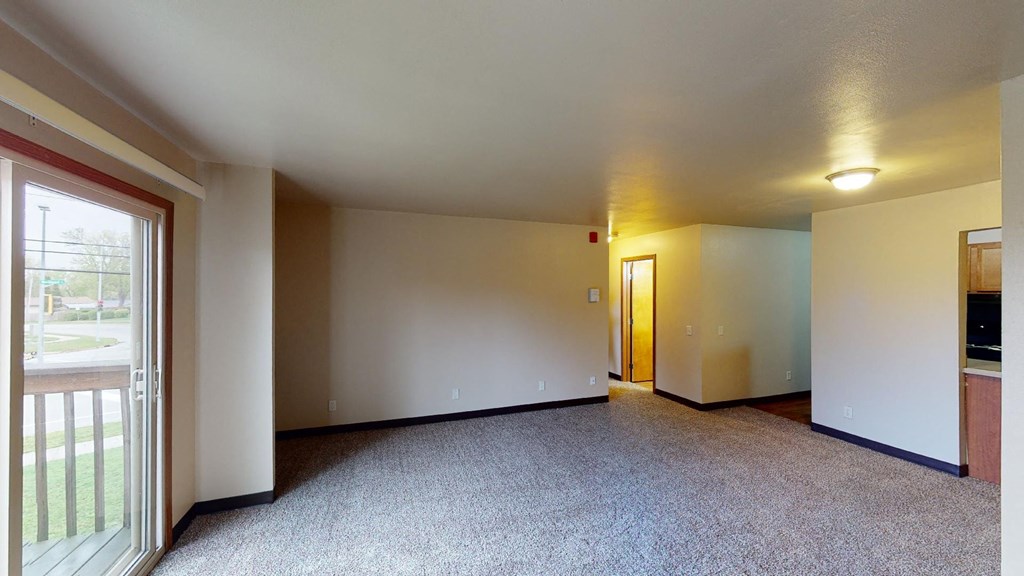 A spacious room with a carpeted floor and a door on the right side.