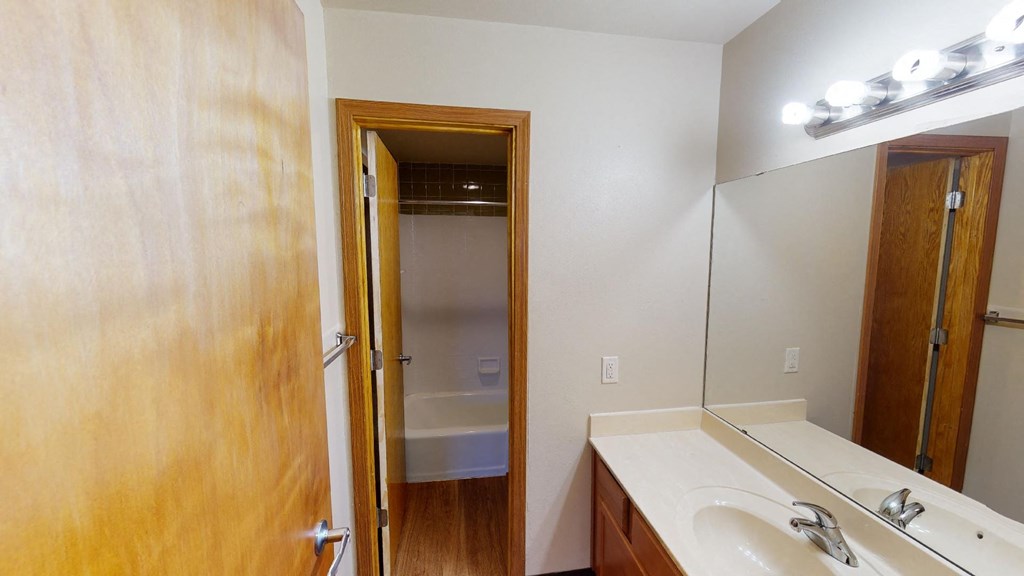 A bathroom with a sink, mirror, and a door.