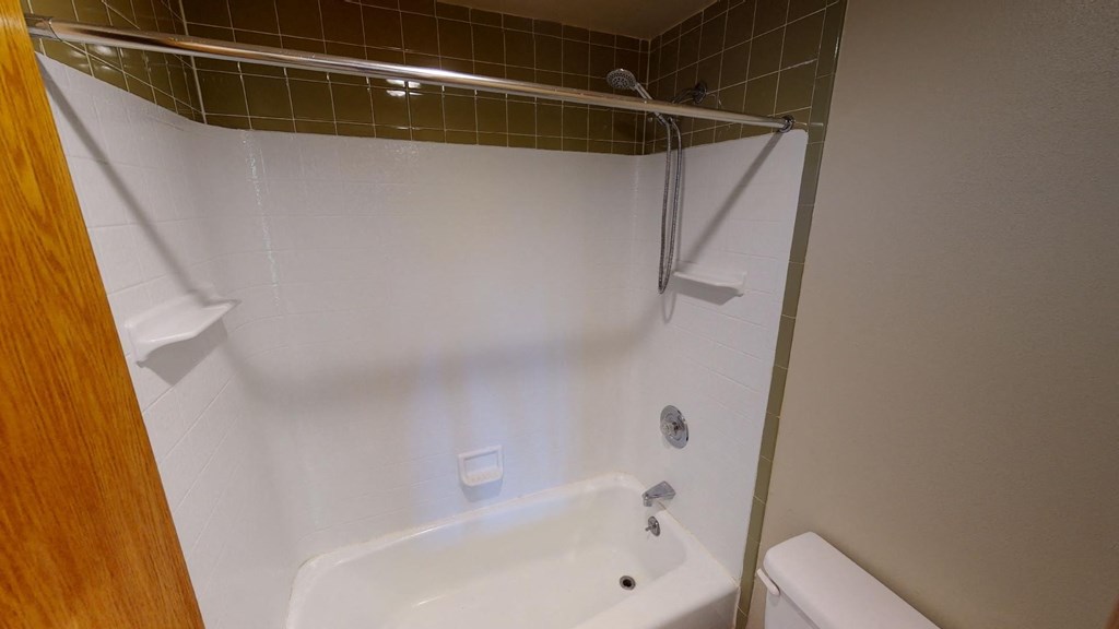 A white bathtub with a shower head and a towel rack.