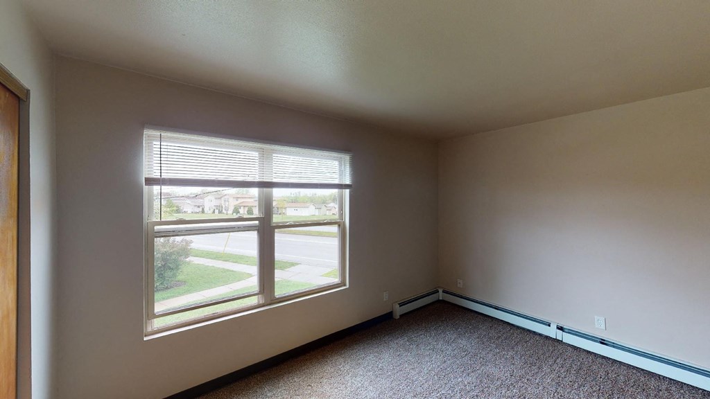 A room with a large window and carpeted floor.
